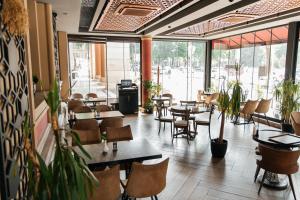 a restaurant with tables and chairs and plants at Ganja Hotel in Ganja