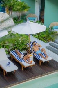 two people laying on chairs under an umbrella at Lomo Boutique Hotel & Villas, Uluwatu in Uluwatu