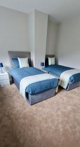 two beds in a bedroom with blue sheets at Rosmore Newport in Newport