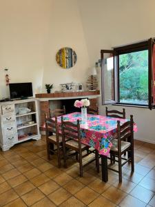 a dining room table with chairs and a table with flowers on it at Casa Merella in Narbolia