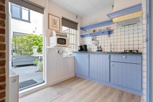 a kitchen with blue cabinets and a microwave at Huisje De Koning in Zandvoort