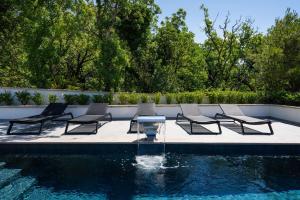 a group of chairs and a table next to a pool at My Dalmatia - Sea View Villa Senti with private pool in Starigrad