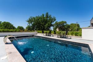a swimming pool with chairs in a backyard at My Dalmatia - Sea View Villa Senti with private pool in Starigrad