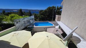 a patio with umbrellas and a swimming pool at Apartmani Darijo in Čelina
