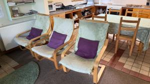 a kitchen with a table and four chairs with purple pillows at Newtonmore Hostel in Newtonmore