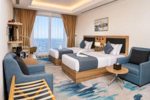 a hotel room with two beds and two chairs at The Proud Hotel Al Khobar in Al Khobar