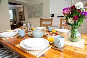 a wooden table with plates and a vase of flowers at Grimsbury Castle in Thatcham
