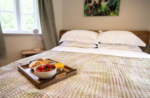 a tray with a bowl of fruit on a bed at Grimsbury Castle in Thatcham