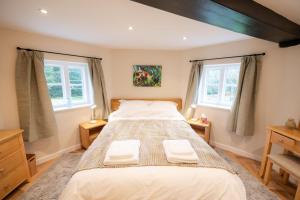 a bedroom with a large bed and two windows at Grimsbury Castle in Thatcham