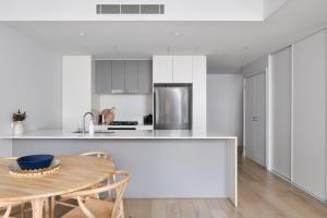 a white kitchen with a wooden table and a dining room at The Ellery in Newcastle