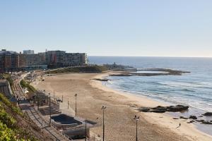 a view of a beach with buildings and the ocean at The Ellery in Newcastle
