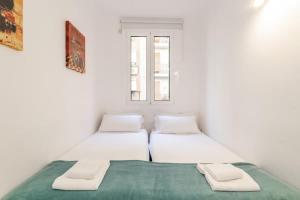 two beds in a white room with a window at Charming central gem in Poble Sec in Barcelona