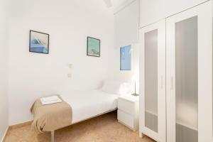 a small white bedroom with a bed and a mirror at Charming central gem in Poble Sec in Barcelona