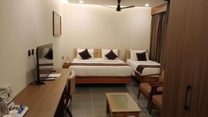 a hotel room with a bed and a desk at Anasvara Hotels in Mysore