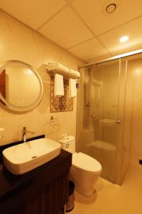 a bathroom with a toilet and a sink and a shower at Anasvara Hotels in Mysore