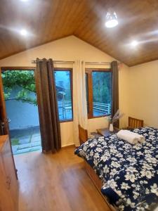 ein Schlafzimmer mit Bett und großen Fenstern in der Unterkunft Annantam in Manali