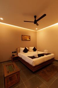 a bedroom with a bed with a ceiling fan at Anasvara Hotels in Mysore