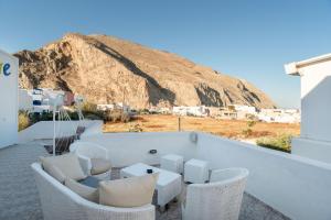 a balcony with chairs and a table and a mountain at Pleasure Blackbeach Studios in Perissa