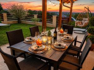 a wooden table with plates and wine glasses on a patio at Gímes Apartman in Cserszegtomaj
