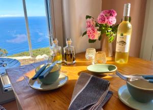 a wooden table with a bottle of wine and a table with plates and bowls at Unique Robinson-House with breathtaking seaview in Podšpilje +46 photos