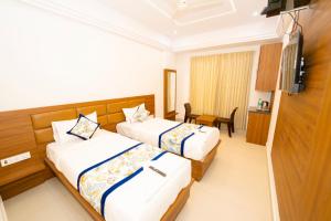 a hotel room with two beds and a television at Sri Sai Lotus In in Bangalore +15 photos