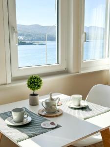 a white table with two tea cups and a window at Apartamento Brisa by ALÔGA in Corcubión