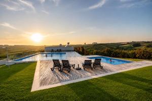 a group of chairs sitting next to a swimming pool at Carina Villas with Pool and Ocean view in Lourinhã