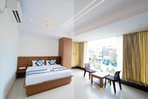 a bedroom with a bed and a table and a window at Sri Sai Lotus In in Bangalore
