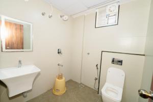 a white bathroom with a sink and a toilet at Sri Sai Lotus In in Bangalore