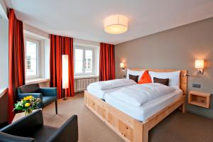 a bedroom with a large bed with red curtains at Hotel Donatz in Samedan