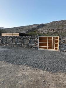 a garage with a wooden gate and a stone wall at Reef ALjabal Rest in Minthār