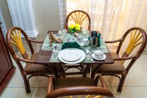 a dining room table with chairs and a table with plates at Grand Forty Garden Ltd in Kisumu