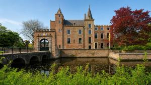 a large brick building with a bridge over a river at Appartement "Hartje Haamstede" in Burgh Haamstede
