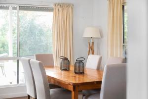 a dining room table with white chairs and a window at Fennell House in Robe +4 photos