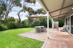 a patio with a table and chairs in a yard at Fennell House in Robe
