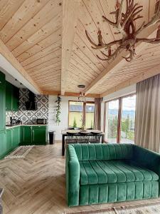 a living room with a green couch and a table at Domki Widokowelove z widokiem na panoramę Tatr - mountain view in Gliczarów