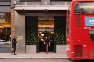 a red double decker bus parked in front of a store at The Hoxton, Shoreditch in London