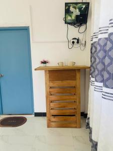 a room with a wooden table and a tv on a wall at Blue Heaven in Mannar
