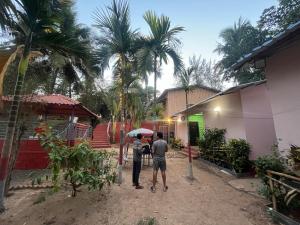 a man and a woman standing under an umbrella at Sai beach Resort in Diveagar