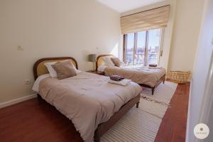 a bedroom with two beds and a large window at Apartamento Ruy Belo - Foz in Vila do Conde