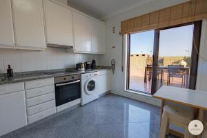 a kitchen with white cabinets and a view of a patio at Apartamento Ruy Belo - Foz in Vila do Conde +5 photos