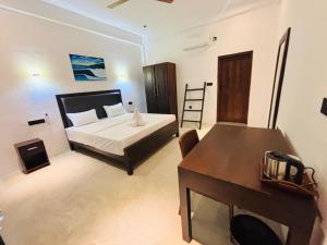 a bedroom with a bed and a desk in it at Surf Arugam in Arugam Bay