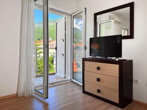 a flat screen tv sitting on a dresser in front of a window at Apartment Orange Blossom First Line & Pool 1 in Bijela
