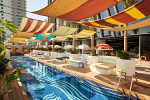 a swimming pool with umbrellas and chairs and a building at Mama Shelter Dubai in Dubai