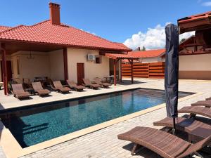a swimming pool with lounge chairs next to a house at Bereg-Travel in Berehove