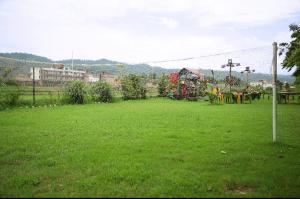 a field of green grass with a playground in the background at Corbett Treat Resort in Rāmnagar