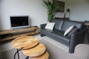a living room with a couch and a table and a tv at Kustverhuur, Oude manege Nieuwvliet, Nieuwvliet 1 - 2 in Nieuwvliet