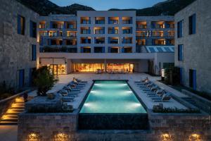 a hotel with a swimming pool in front of a building at Mövenpick Hotel & Residences Teuta Kotor Bay in Kotor
