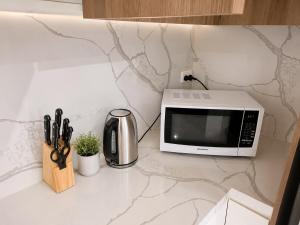 a microwave sitting on top of a kitchen counter with scissors at Modern Private Granny Flat Free Parking in Riverstone +7 photos