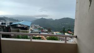 a balcony with a view of a city and mountains at Hotel sunrise in Kodaikānāl